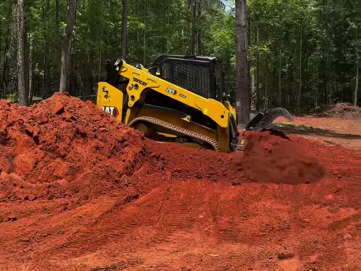 Track loader shaping a pile of red dirt on a grading job